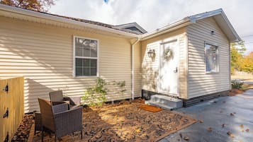 Welcome to a cozy home with a charming entrance featuring a white door, wicker chair, and a small porch.