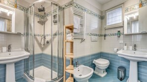Un baño con ducha de vidrio, lavamanos, un bidé y un inodoro.