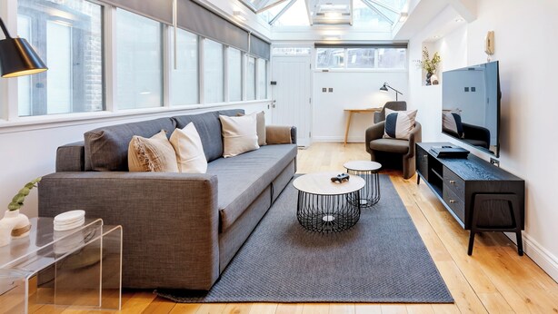 A modern living room with a large window, a sofa, a coffee table, a TV, and a small side table. - 2Bedr/3Beds/2Bath Covent Garden 3min subway (London)