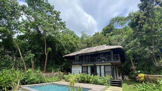 Uma casa de dois andares com piscina em um jardim exuberante.