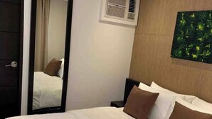 Quarto de hotel com cama, espelho, ar-condicionado fixado na parede e um quadro.