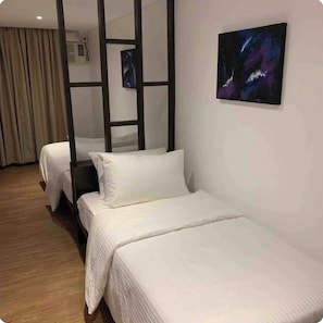 Two single beds with white bedding, a framed artwork, and a large window.