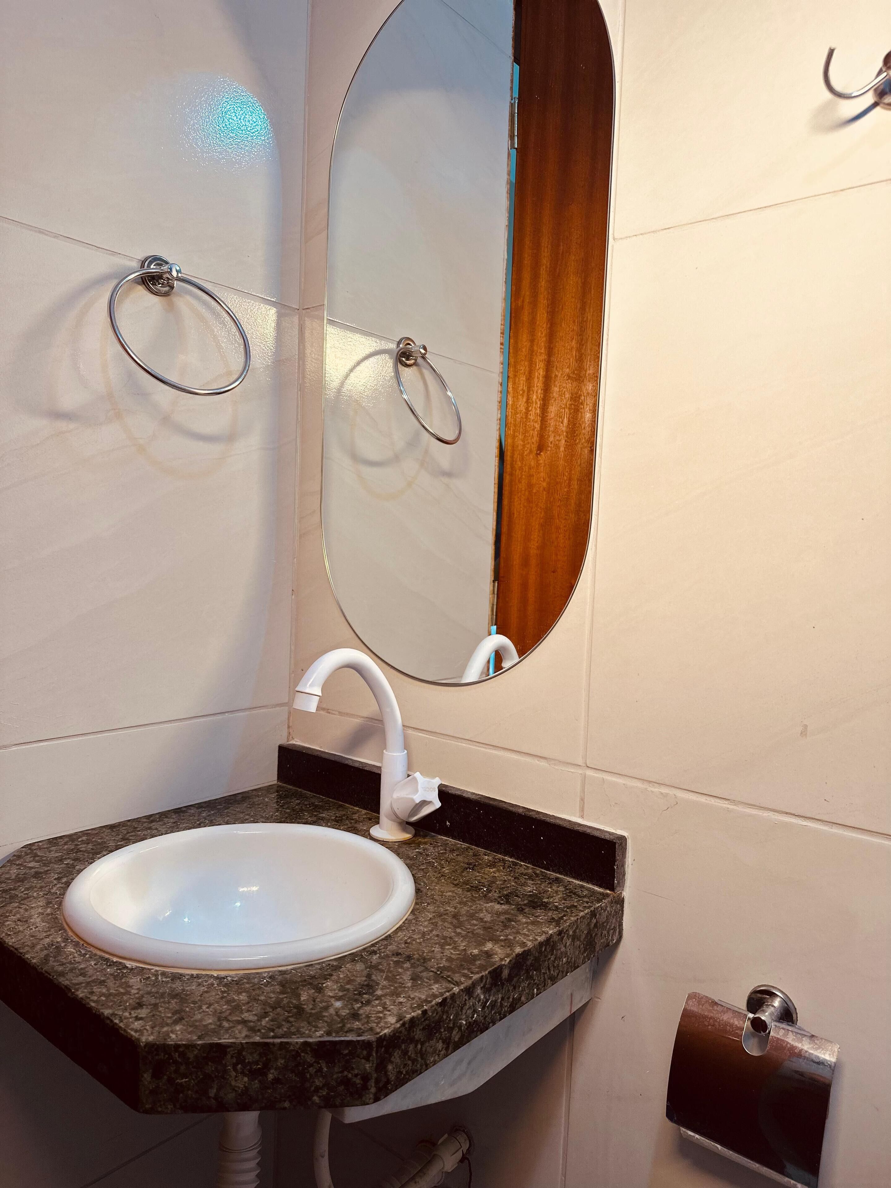 A bathroom with a granite countertop sink, a white faucet, and a mirror with a wooden frame.