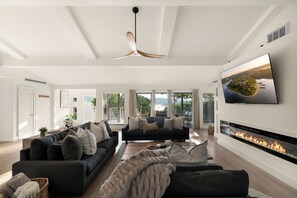 A modern living room with a fireplace, a sofa set, and a large TV screen. - Lakeview Home with Sunset Deck & Firepit - Near SDC - Resort Access (Branson)
