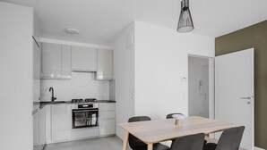 A modern kitchen with white cabinets, a stove, and a dining area with a table and chairs.
