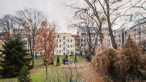 A courtyard with a building in the background, surrounded by trees and a grassy area.