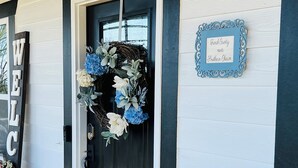 A black door with a floral wreath, a welcome sign, and a sign stating 'French Country meets Southern Charm'. - French Country Retreat Near Ball Ground Weddings, girls getaway. Quiet retreat!  (Ball Ground)