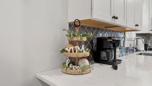 A kitchen with white cabinets, a coffee maker, and a decorative wooden stand with flowers and the word "LOVE". - French Country Retreat Near Ball Ground Weddings, girls getaway. Quiet retreat!  (Ball Ground)