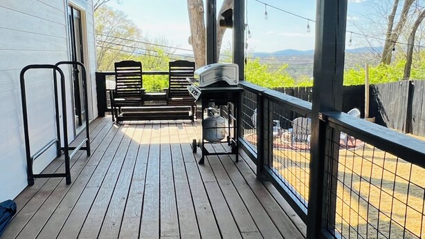 A covered wooden deck with a view of a fenced area and distant hills. - French Country Retreat Near Ball Ground Weddings, girls getaway. Quiet retreat!  (Ball Ground)
