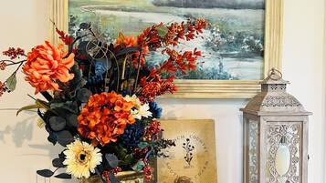 A decorative arrangement on a dark wooden surface including a vase with flowers, a lantern, and a framed picture.