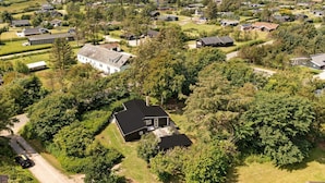 Vista aérea de uma área residencial com casas, áreas verdes e um corpo d'água ao fundo.
