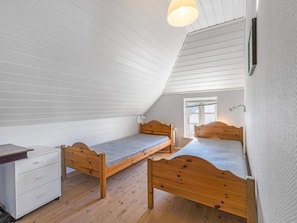 A room with two wooden beds, a desk, and a window.
