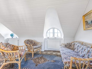 A loft bedroom with a high ceiling, a large window, and a rattan sofa.
