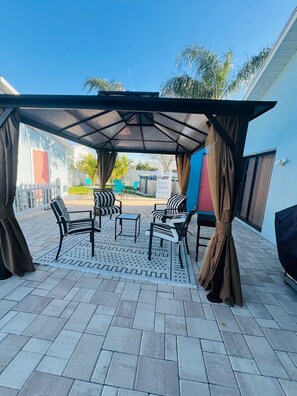 Relax in a shaded patio area with a patterned rug and comfortable seating.