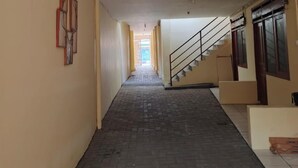 Ein langer, schmaler Korridor mit Backsteinboden und einer Treppe auf der rechten Seite.