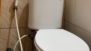 Eine Toilette mit weißem Tank und Sitz, verbunden mit einem an der Wand montierten Spülhebel.