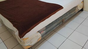 Ein Einzelbett mit schwarzem Kopfteil, weißen Kissen, einer braunen Decke und einem Matratze mit sichtbarem Markenetikett.