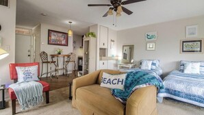 A cozy bedroom with a bed, a chair, a ceiling fan, and a desk with a chair.