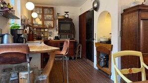 A kitchen with a wooden table, chairs, a stove, a microwave, and various kitchen appliances.