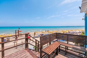 A wooden deck with a view of a beach with umbrellas and people.