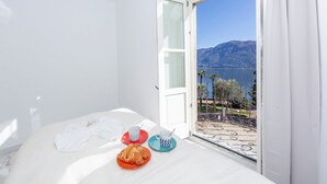 Ett rum med en säng, ett bord med en tallrik mat på och en utsikt över ett bergigt landskap genom ett fönster.