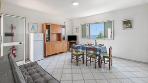 Un espacio habitable compacto con zona de comedor, kitchenette y sofá.