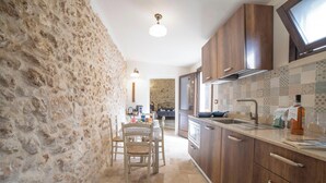A kitchen with stone walls, wooden cabinets, and a tiled backsplash.