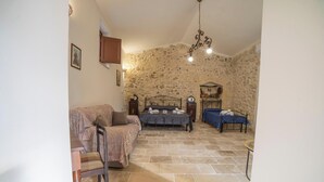A bedroom with a stone wall, a bed, a sofa, and a small table.