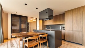 A modern kitchen with wooden cabinets, a central island, and a dining area with wooden chairs. - OCEANFRONT LUXURY CONDO IN TULUM/TANKAH WITH BEACHCLUB (Tulum)