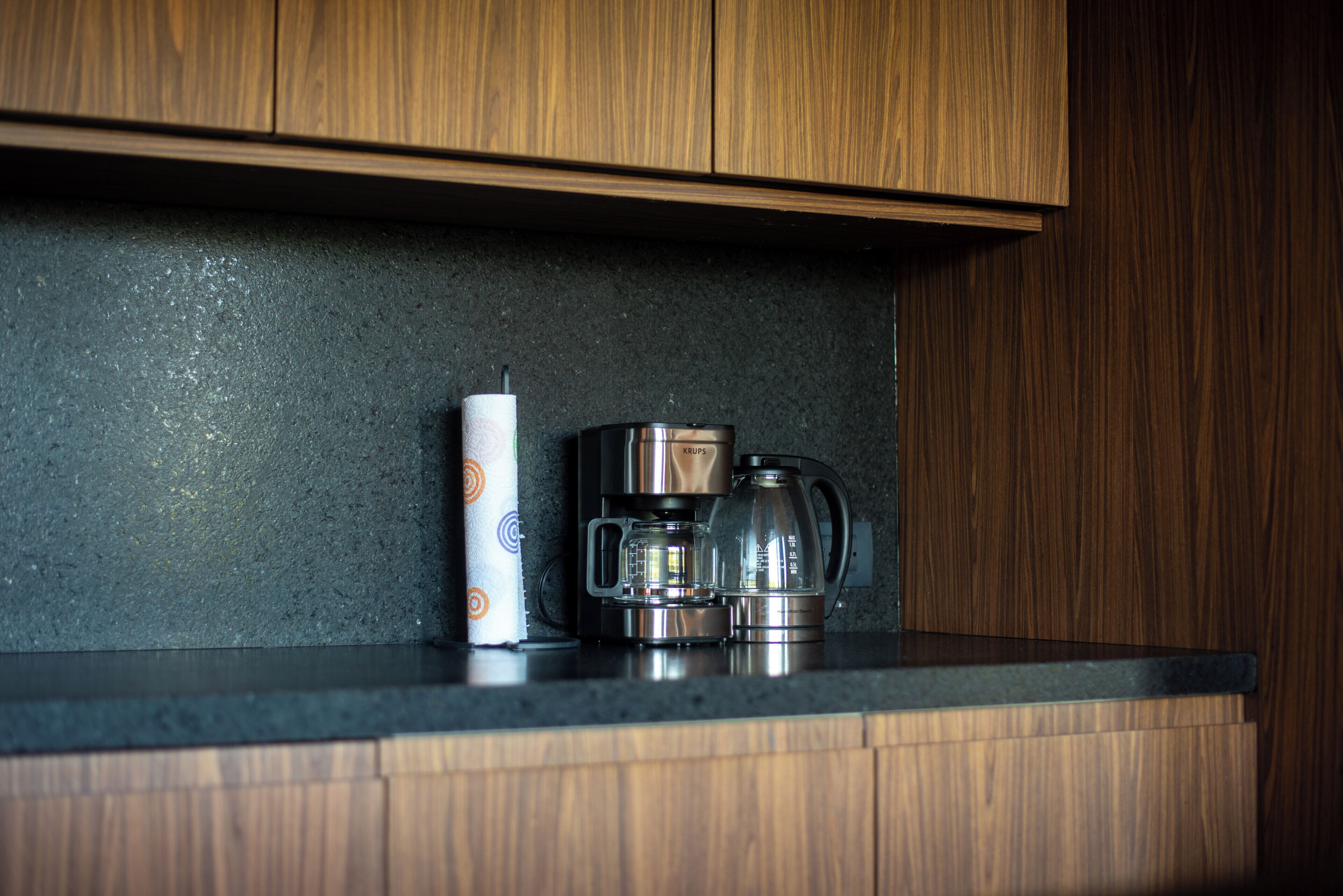 A kitchen counter with a coffee maker and a roll of paper towels.