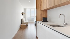 Une cuisine moderne dotée d’un évier en acier inoxydable, de meubles en bois et offrant une vue sur l’extérieur.