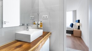 Une salle de bain moderne avec un lavabo blanc, un plan de travail en bois et un grand miroir.