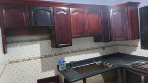 A kitchen with dark wooden cabinets, a tiled backsplash, and a black countertop. - House 2nd level near AILA!!!! (Santo Domingo Este)