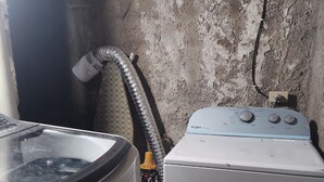A laundry area with a washing machine and a dryer, a hose, and a power outlet on the wall. - House 2nd level near AILA!!!! (Santo Domingo Este)