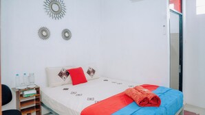 Un dormitorio ordenado con cama, almohadas, una mesita de noche con botellas de agua y adornos en la pared.