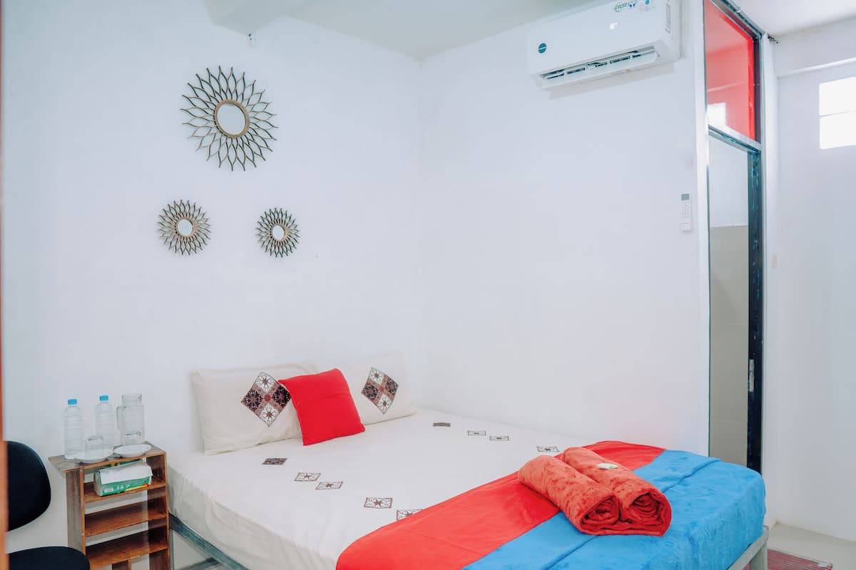 Une chambre à coucher bien rangée, avec un lit, des oreillers, une table de chevet sur laquelle sont posées des bouteilles d’eau, et des décorations murales.