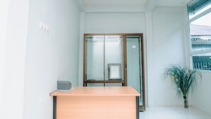 Una habitación con un escritorio de madera, una puerta de cristal y una planta en maceta.