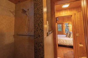 A wooden cabin interior with a shower, a bed, and a window. - Mountain Studio for Two! Hot Tub+Firepit+EV! (Ashford)