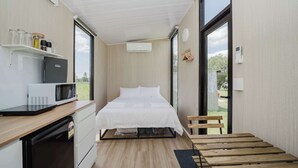 Une petite chambre comprenant un lit, un four à micro-ondes, un réfrigérateur et une petite table.