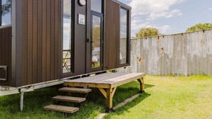 Une cabane moderne dotée d’une porte coulissante, d’une petite terrasse et d’une table de pique-nique.