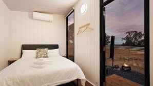 Une chambre avec un lit, un portant à vêtements et une vue sur un feu à l’extérieur.