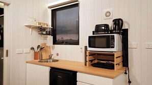 Une cuisine compacte équipée d’un four à micro-ondes, d’une machine à café et d’un comptoir en bois.