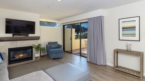 A modern living room with a fireplace, a television, a sofa, and a sliding glass door leading to a balcony. - Seascape-updated ground floor 1 bedroom! (Aptos)