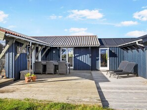 Un espace extérieur abrité, doté d’une terrasse, de tables, de chaises et de plantes en pot.
