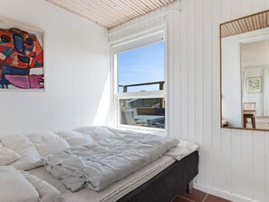 A bedroom with a bed, a window, a painting, and a mirror. - 5 Star Holiday Home in Lokken (Lokken)
