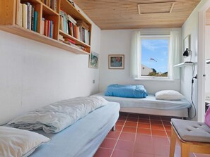 A room with two beds, a bookshelf, a window with a view, and a desk with a lamp. - 5 Star Holiday Home in Lokken (Lokken)