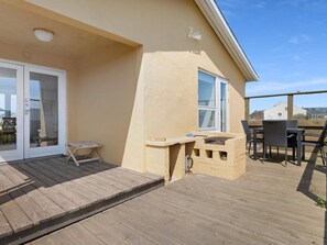 A wooden deck with a table and chairs, a sliding glass door, and a window. - 5 Star Holiday Home in Lokken (Lokken)