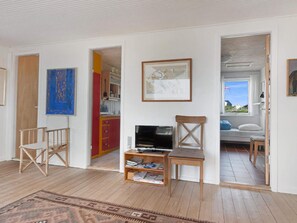 A room with a wooden floor, a bookshelf, a television, and a window with a view of the outside. - 5 Star Holiday Home in Lokken (Lokken)