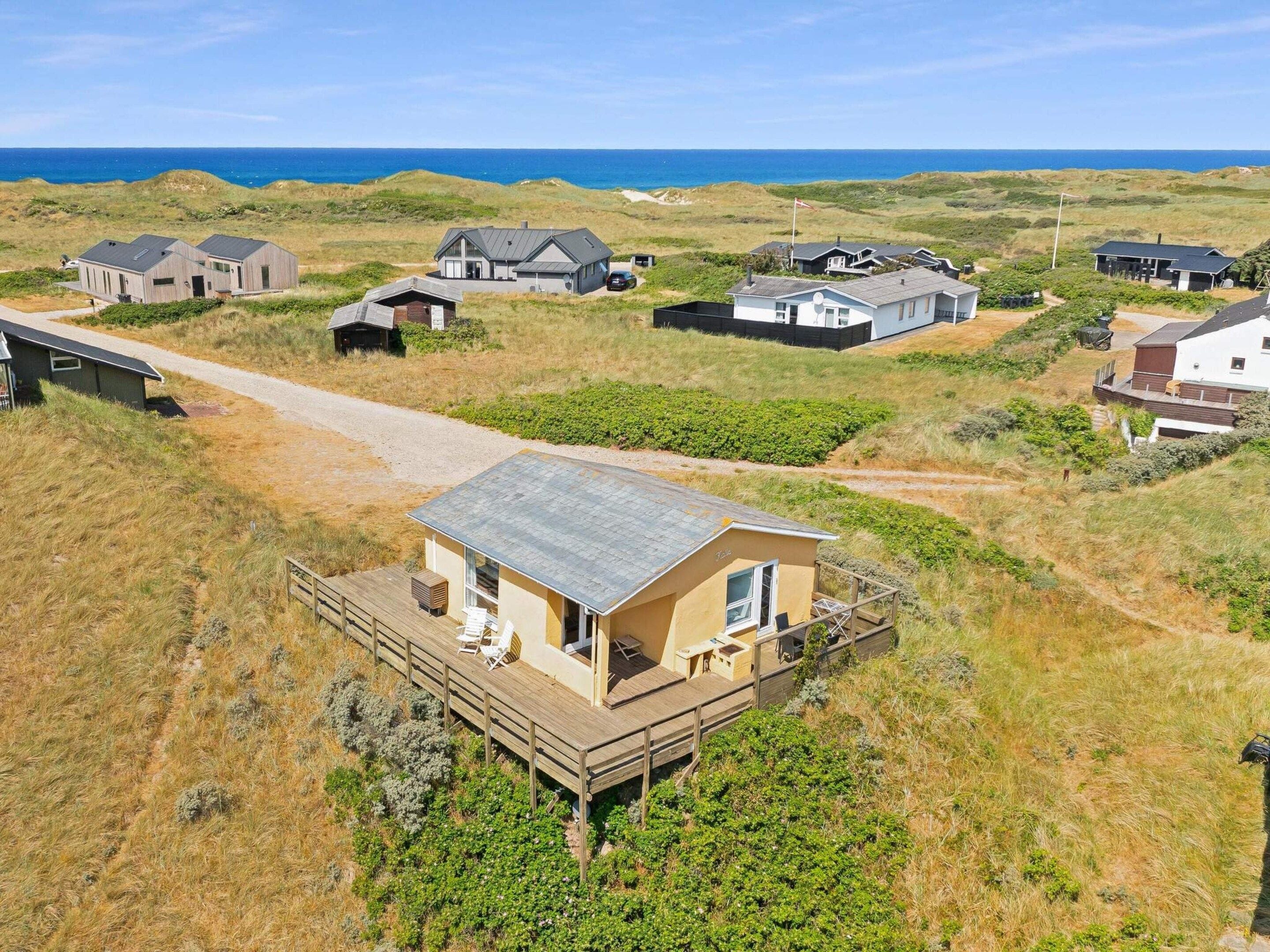 A coastal property with multiple houses, a wooden deck, and a view of the sea.