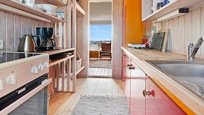A compact kitchen with wooden cabinetry, a built-in stove, and a view through an open doorway to a balcony.